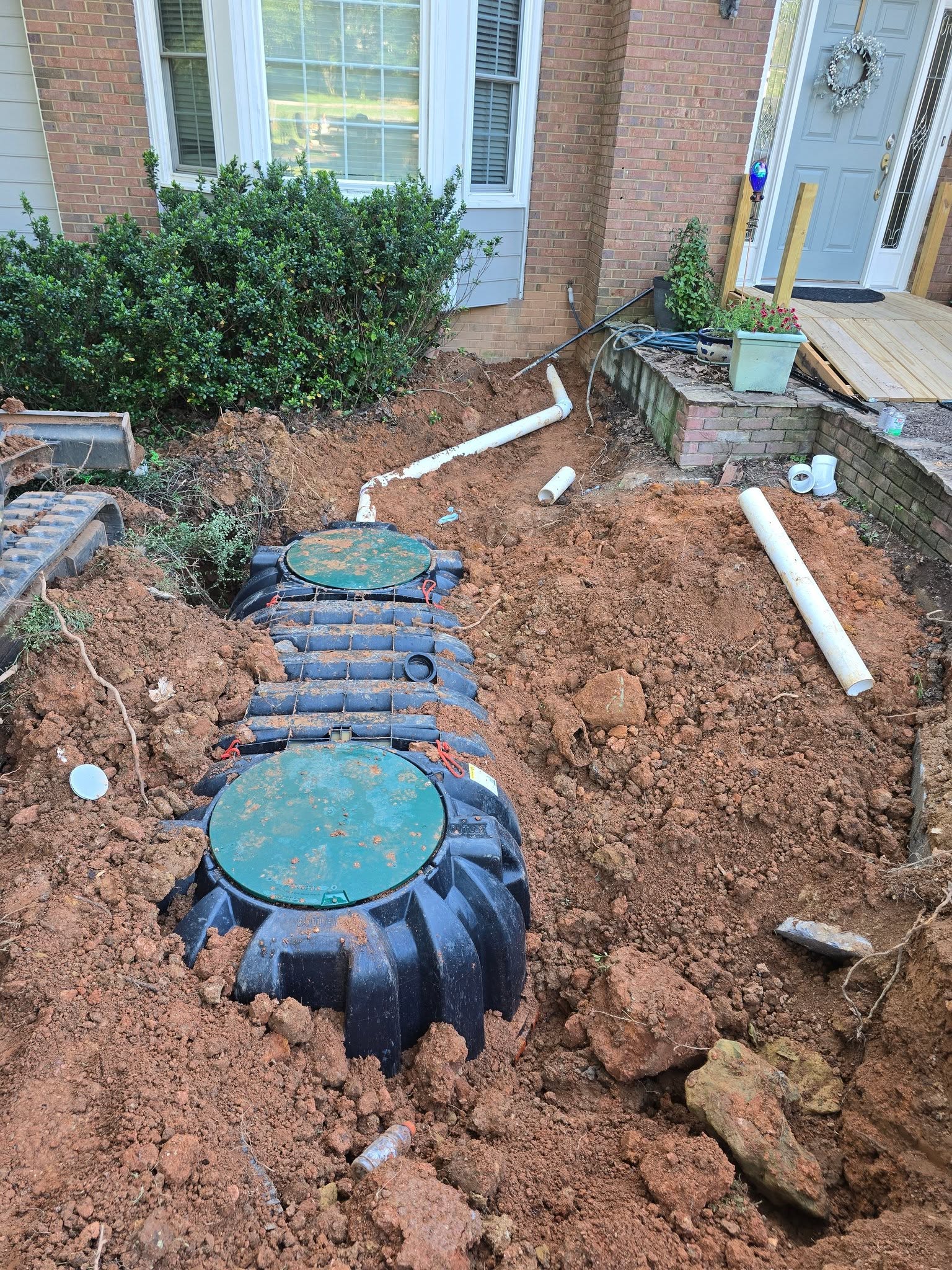 Before — new septic tank set in an open pit beside a brick home
